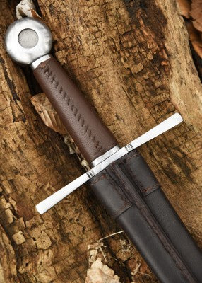 Épée d’armes à pommeau en roue – poignée brune cousue et pommeau acier – gros plan avec fourreau cuir noir, sur écorce près