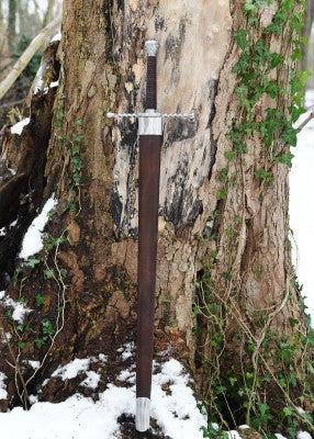 Épée bâtarde à pommeau en coquille cannelée – épée au fourreau cuir contre tronc, neige au sol, reconstitution médiévale