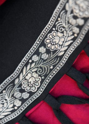 Détail du galon décoratif noir et or sur robe Eleanor rouge noir, finition soignée et contraste visuel