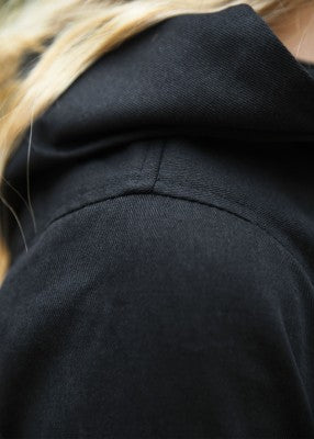 Détail de la capuche cousue sur robe médiévale Isra noire en coton, finition simple et tombé naturel