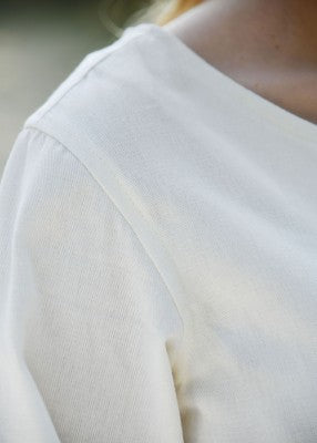 Robe médiévale Milla naturel – gros plan épaule et couture de manche, tissu sergé en coton léger, détail matière en extérieur