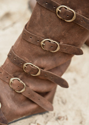 Détail des cinq boucles en laiton sur bottes médiévales marron en cuir suédé, système de fermeture de la cheville au mollet