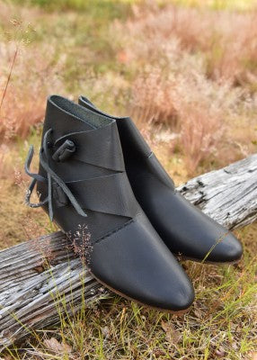 Paire de chaussures vikings Jorvik noires posée sur un tronc, avec tige montante et fermeture en cuir