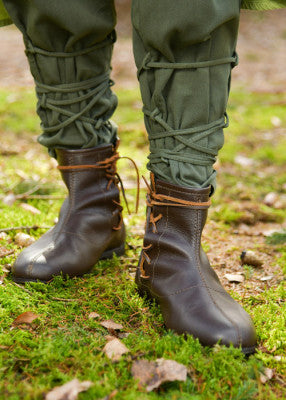 Bottines médiévales en cuir brun foncé portées aux pieds, avec laçage latéral, pour reconstitution, GN ou LARP