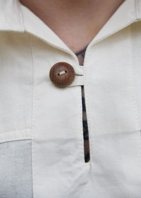 Détail du col simple et du bouton en bois de la chemise Götz naturelle en coton