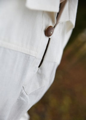 Détail de l’ouverture boutonnée de la chemise Götz naturelle, avec bouton en bois et couture latérale