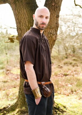 Chemise manches courtes brune portée de profil, avec col lacé et coupe ample