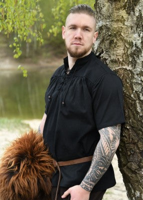 Chemise manches courtes noire portée de trois quarts, avec col lacé et coupe ample