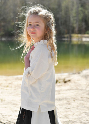 Chemisier Birga pour enfant en coton blanc, porté de profil au bord de l’eau avec coupe légère pour reconstitution, GN ou LARP enfant