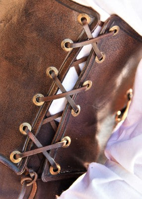 Détail du laçage du corsage sous-poitrine en cuir brun, avec œillets métalliques couleur laiton