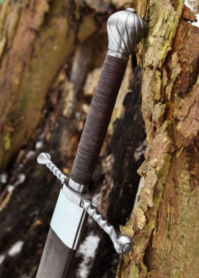 Épée bâtarde à pommeau en coquille cannelée – poignée brune et pommeau acier – détail du manche et quillon torsadé, sur tronc