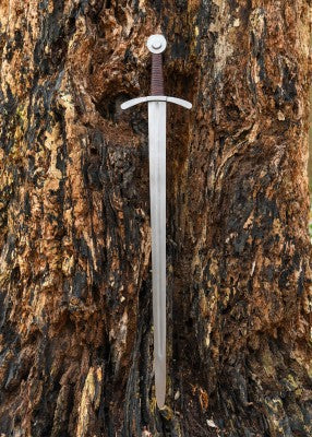 Épée de croisé à pommeau en disque, acier gris, vue entière de l’épée sur tronc, reconstitution médiévale et combat scénique