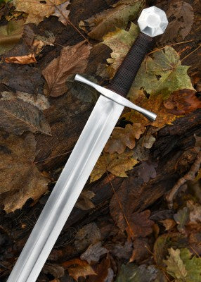 Épée de croisé à pommeau octogonal – lame grise longue et garde droite – vue en diagonale sur feuilles mortes, extérieur