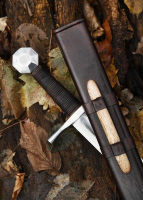 Épée de croisé à pommeau octogonal – poignée brune enroulée et garde droite – gros plan avec fourreau cuir brun sur feuilles