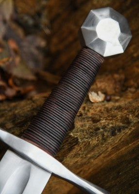 Épée de croisé à pommeau octogonal – poignée brune enroulée et pommeau acier – gros plan sur la prise et le pommeau, sur bois