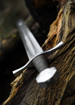 Épée de croisé à pommeau octogonal – lame grise et garde droite – vue en perspective le long de la lame, posée sur vieux bois