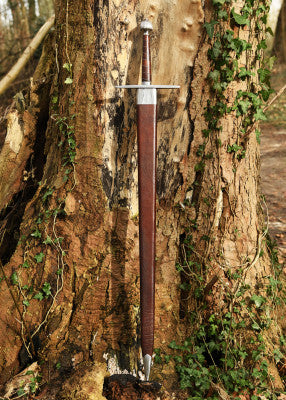 Épée longue à pommeau en poire cannelée – fourreau cuir brun vertical – vue complète contre tronc d’arbre, lierre en forêt