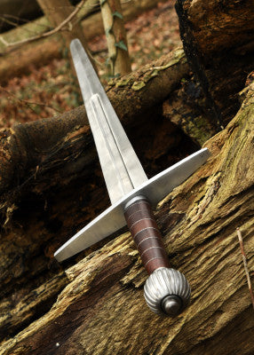 Épée longue à pommeau en poire cannelée – lame grise et garde droite – vue en perspective le long de la lame, posée sur bois