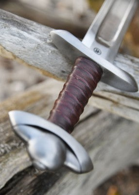 Épée viking type Petersen L, acier gris et cuir brun, vue entière posée sur bois, combat scénique pour GN et LARP médiéval