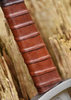 Épée viking à pommeau trilobé, acier gris et cuir brun, vue entière posée contre arbre, reconstitution médiévale et LARP