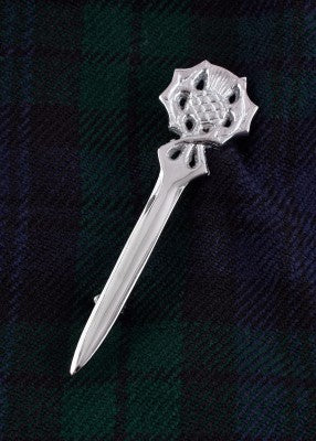 Épingle de kilt motif chardon en laiton chromé, présentée sur tissu écossais tartan