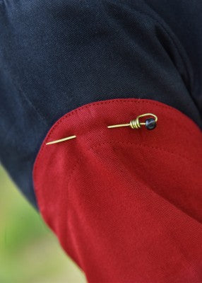 Détail d’une manche amovible rouge fixée sur une tenue à l’aide d’une épingle décorative