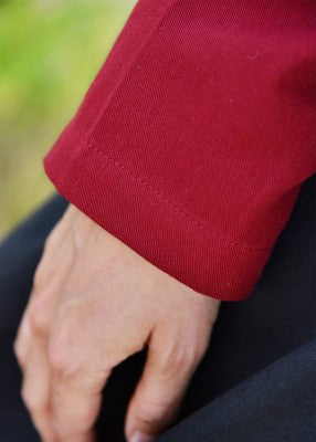 Détail du bas d’une manche amovible rouge en coton, montrant la finition simple du poignet