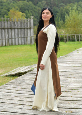 Vue de profil de la robe tablier viking Annik brune portée sur robe claire en reconstitution historique, GN et LARP