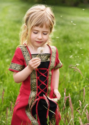 Robe Eleanor pour enfant en coton rouge-noir, portée de face en extérieur dans l’herbe pour reconstitution, GN ou LARP enfant