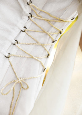 Détail du laçage latéral du corsage blanc Fine avec cordon clair et œillets métalliques, pour ajuster la robe