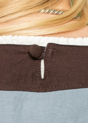 Détail de la fermeture au dos de la robe Gudrun bleu-gris et brun avec bouton recouvert
