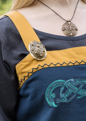 Détail de la bretelle, de la broche et de la broderie Jelling sur la robe tablier viking Hilja bleu et jaune