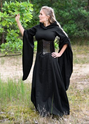 Robe médiévale Isra noire portée en extérieur, coton fluide, silhouette longue sobre avec capuche généreuse