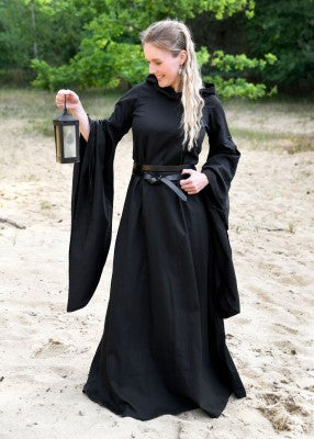 Robe médiévale Isra noire portée debout, manches trompette larges, tombé fluide et présence marquée