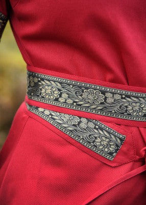 Détail de la ceinture et du galon décoratif de la robe bliaut Joséphine rouge, avec motif floral sur tissu contrasté