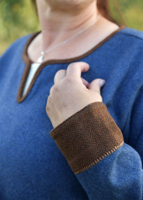 Détail de la manche de la robe viking Lykka bleue avec parement brun à tissage losangé