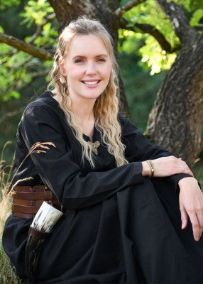 Robe médiévale Milla noir – vue assise portée en extérieur, robe coton ample et encolure fendue, tenue viking avec accessoire