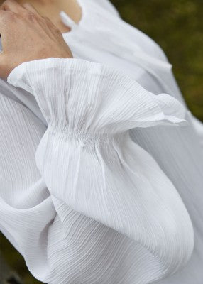 Détail de la manche de la sous-robe légère blanche, avec tissu plissé effet froissé et poignet resserré par élastique