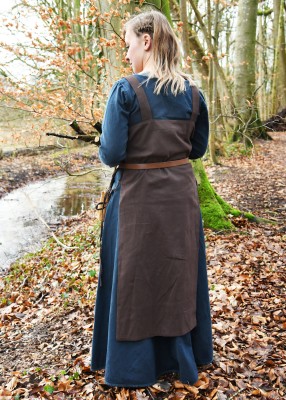 Vue de dos du tablier viking Tinna brun, porté sur une robe bleu foncé avec ceinture et coupe ouverte