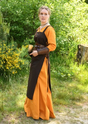 Tablier viking Tinna brun porté de profil sur une robe ocre, avec fente latérale et coupe ouverte