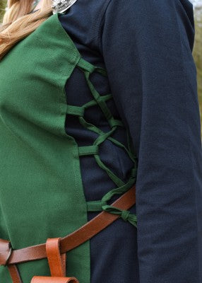 Détail du laçage latéral du tablier viking Tinna vert, porté sur une robe bleu foncé