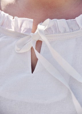 Détail de l’encolure de la tunique Birga blanche, avec petite ruche et lien de fermeture