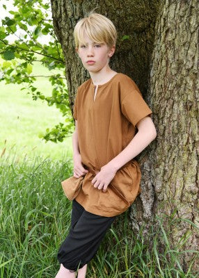 Tunique Linus à manches courtes pour enfant en coton marron, portée en extérieur contre un arbre pour reconstitution, GN ou LARP enfant